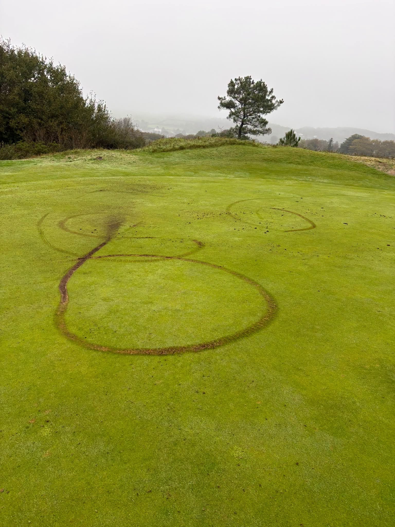 Bikers ride across 12th green at Ashburnham Golf Club, leaving deep tyre marks